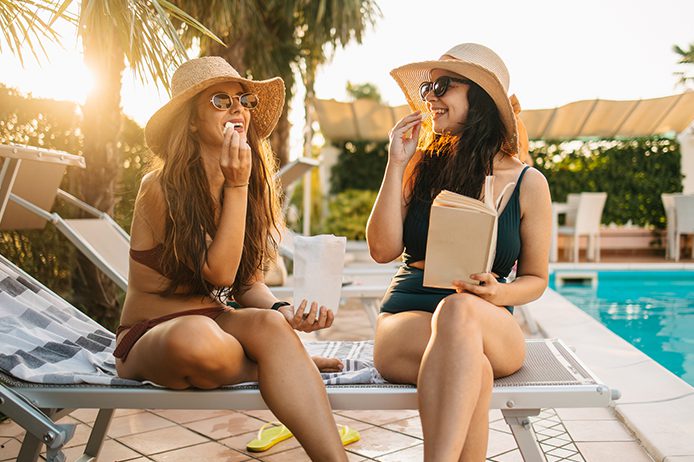 Two young women relaxing by the pool